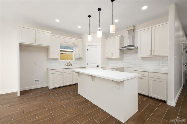 kitchen with backsplash, wall chimney exhaust hood, a center island, and wood tiled floor
