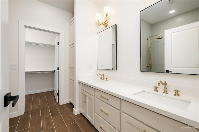 full bathroom featuring a spacious closet, a tile shower, a sink, and double vanity