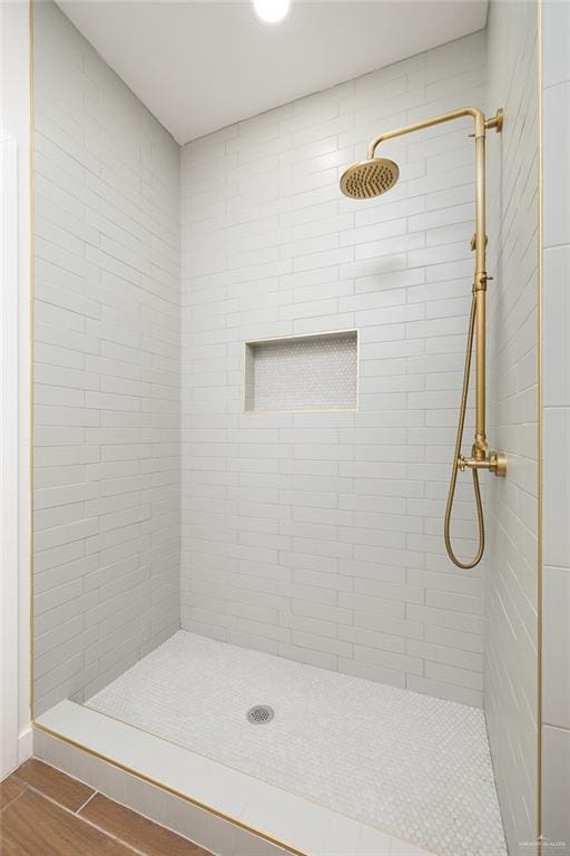 bathroom with a tile shower and wood finished floors