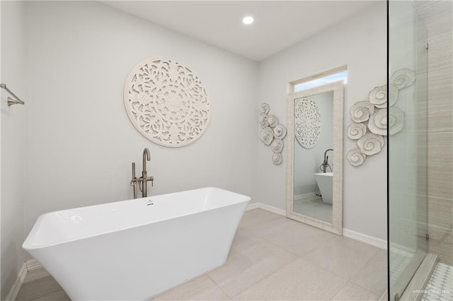bathroom featuring baseboards, recessed lighting, a freestanding bath, and tile patterned floors