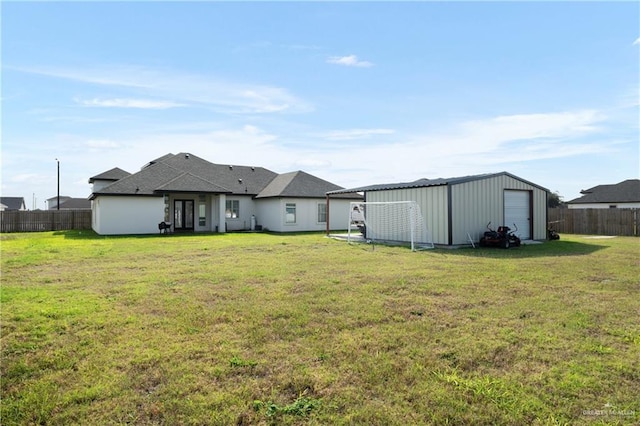 back of property with fence, an outbuilding, a lawn, and a garage