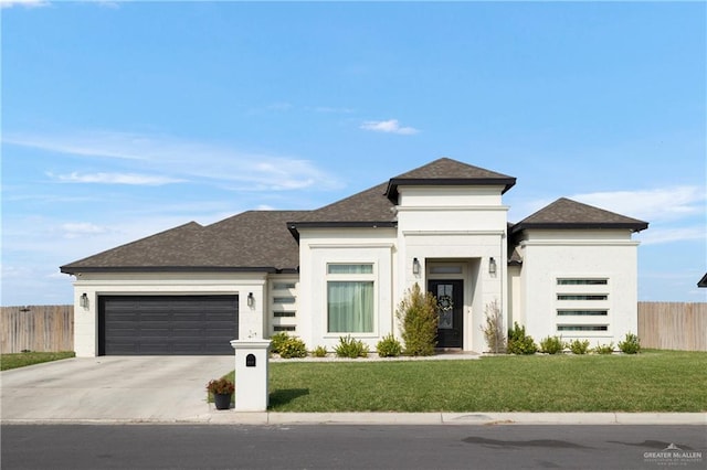 prairie-style home with fence, a shingled roof, a garage, a front yard, and driveway