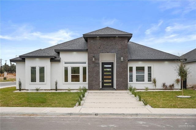 view of front of home featuring a front lawn, roof with shingles, and stucco siding