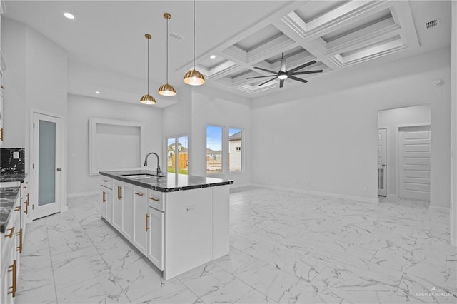 kitchen featuring pendant lighting, a center island with sink, a towering ceiling, open floor plan, and white cabinets