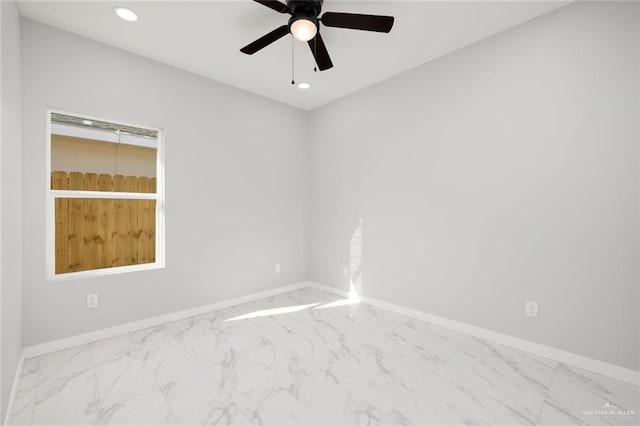 spare room with a ceiling fan, recessed lighting, marble finish floor, and baseboards