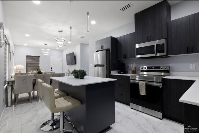 kitchen featuring marble finish floor, stainless steel appliances, and dark cabinets