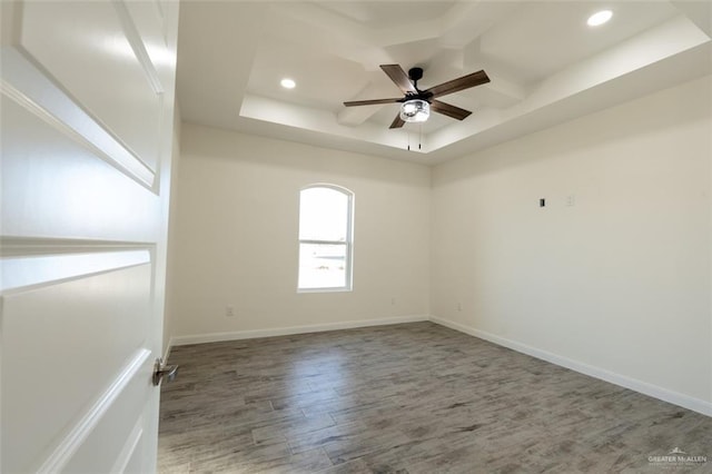 spare room with a tray ceiling, ceiling fan, and hardwood / wood-style floors