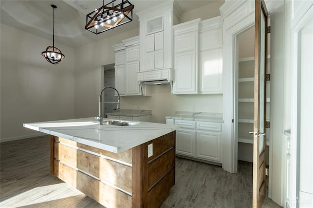 kitchen featuring white cabinetry, hanging light fixtures, and a kitchen island with sink