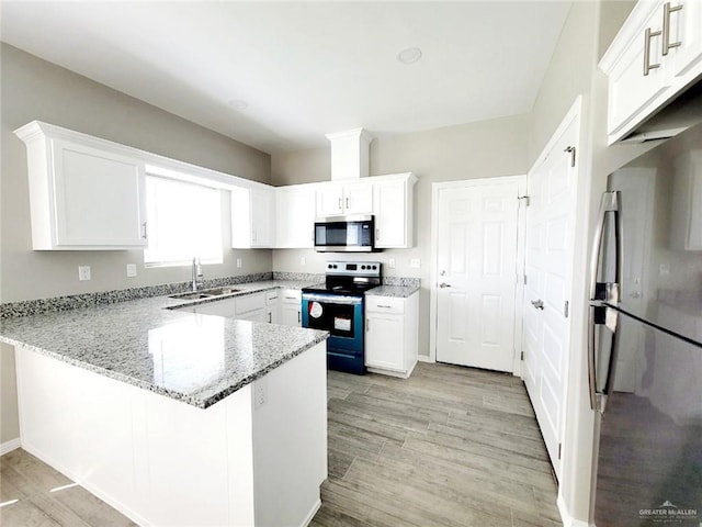 kitchen featuring kitchen peninsula, light wood-type flooring, appliances with stainless steel finishes, light stone counters, and white cabinetry