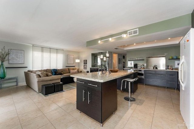 kitchen with a breakfast bar, light tile patterned floors, a kitchen island, and white fridge with ice dispenser