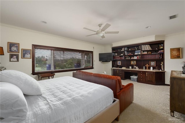 bedroom with crown molding, built in desk, light colored carpet, visible vents, and a ceiling fan