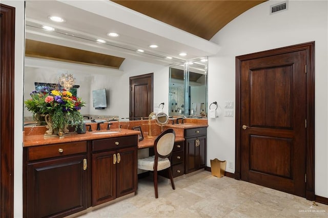 full bathroom with lofted ceiling, double vanity, visible vents, and a sink