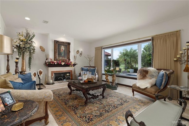 living area with a fireplace with raised hearth, visible vents, and recessed lighting