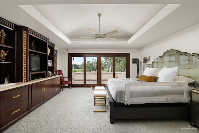 bedroom with ceiling fan, light colored carpet, access to exterior, french doors, and a tray ceiling