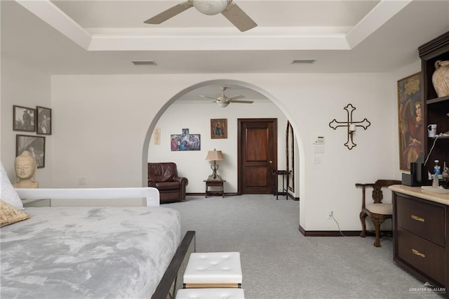 bedroom with visible vents, a tray ceiling, and arched walkways