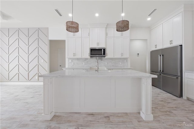 9817 Heights, Harlingen, TX 78552 - kitchen with appliances with stainless steel finishes, decorative backsplash, white cabinets, a center island with sink, and light stone countertops