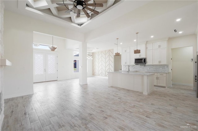 9817 Heights, Harlingen, TX 78552 - kitchen featuring stainless steel microwave, open floor plan, light wood-style floors, backsplash, and white cabinets