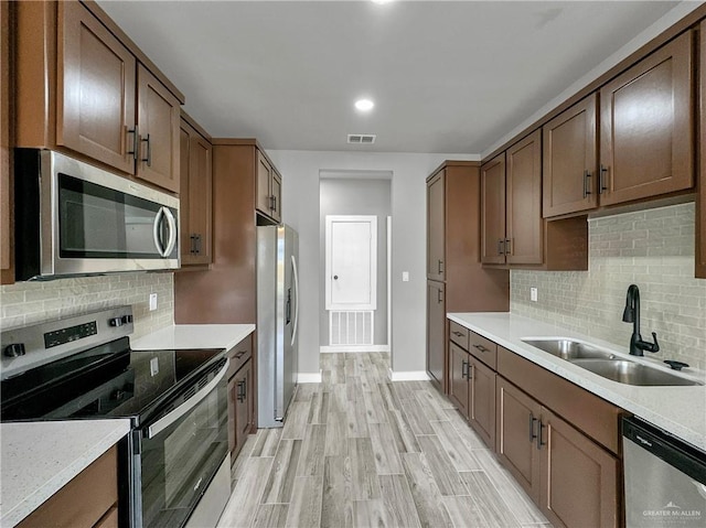 kitchen featuring tasteful backsplash, sink, light hardwood / wood-style flooring, and stainless steel appliances