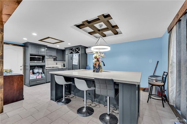 kitchen featuring stainless steel appliances, an island with sink, hanging light fixtures, gray cabinetry, and coffered ceiling