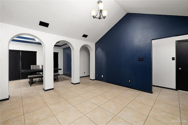 spare room with an inviting chandelier, light tile patterned floors, and vaulted ceiling