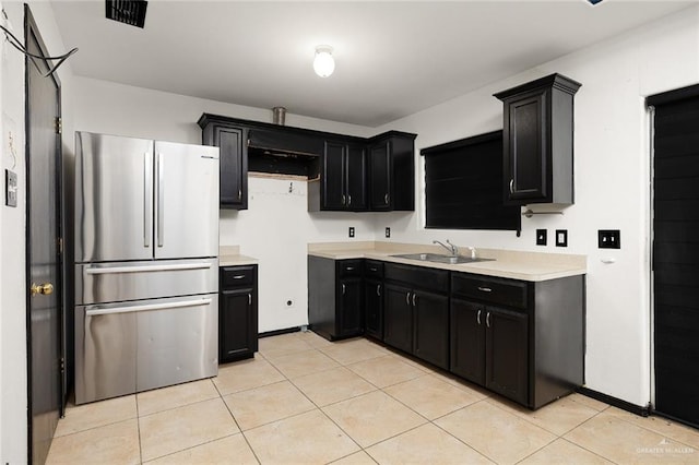 kitchen featuring sink, light tile patterned floors, and stainless steel fridge