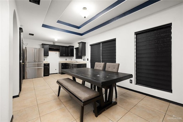 tiled dining room featuring sink and a raised ceiling