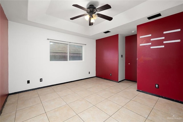 tiled spare room featuring ceiling fan and a raised ceiling