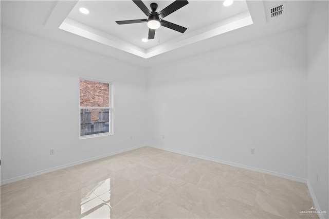 unfurnished room featuring ceiling fan and a raised ceiling