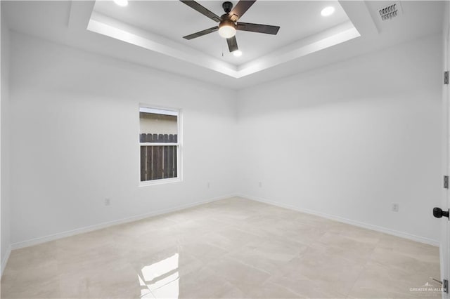 spare room featuring a raised ceiling and ceiling fan