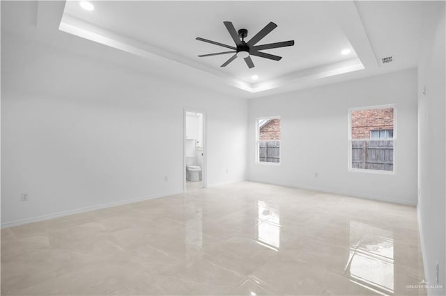 spare room featuring ceiling fan and a raised ceiling