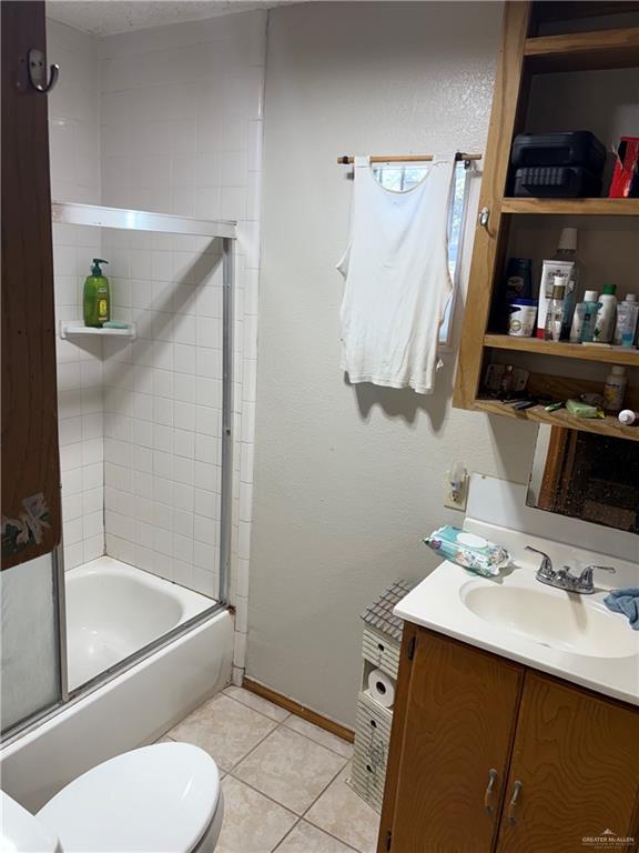 full bathroom with tile patterned flooring, vanity, enclosed tub / shower combo, and toilet