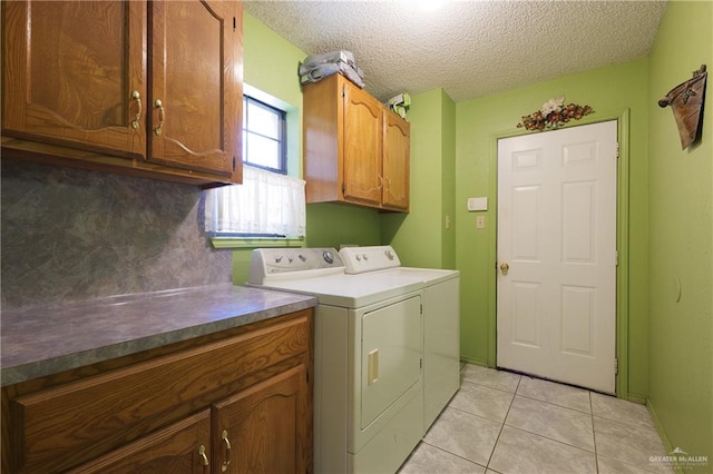 washroom with separate washer and dryer, light tile patterned floors, cabinets, and a textured ceiling