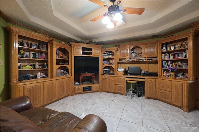 office space with a raised ceiling, ceiling fan, light tile patterned floors, and a textured ceiling