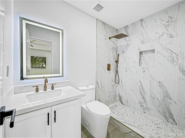 bathroom featuring toilet, vanity, and tiled shower