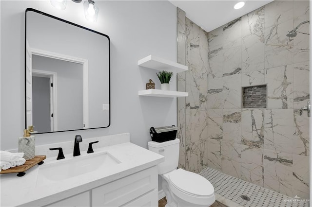 bathroom with vanity, toilet, and tiled shower