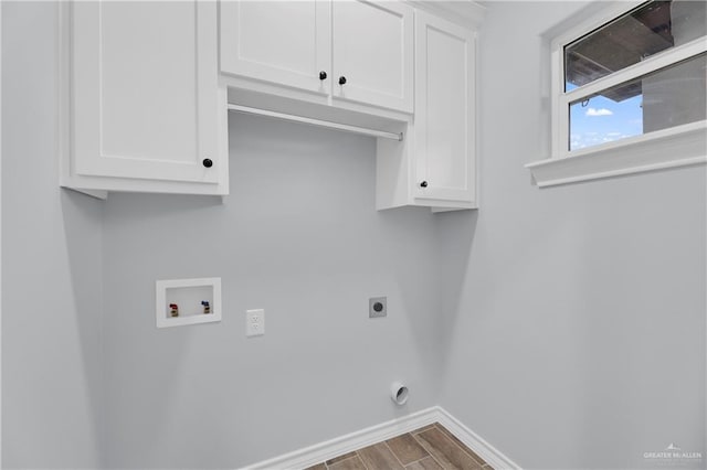 clothes washing area with electric dryer hookup, cabinets, hardwood / wood-style floors, and washer hookup