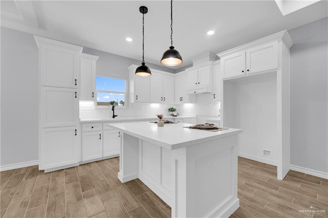 kitchen with decorative backsplash, a center island, light hardwood / wood-style floors, white cabinetry, and hanging light fixtures