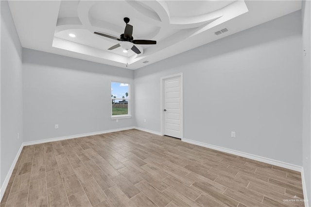 empty room featuring a raised ceiling, ceiling fan, light hardwood / wood-style floors, and coffered ceiling