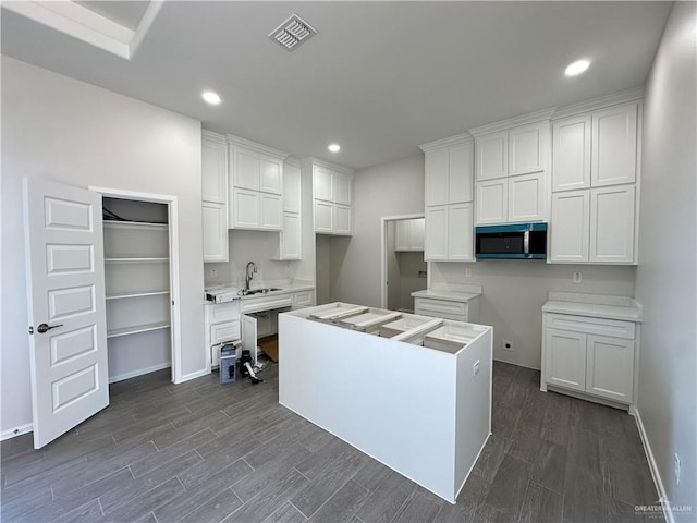 kitchen with stainless steel microwave, visible vents, dark wood-style floors, and a center island