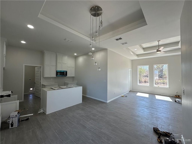 kitchen with visible vents, dark wood-type flooring, stainless steel microwave, open floor plan, and a raised ceiling