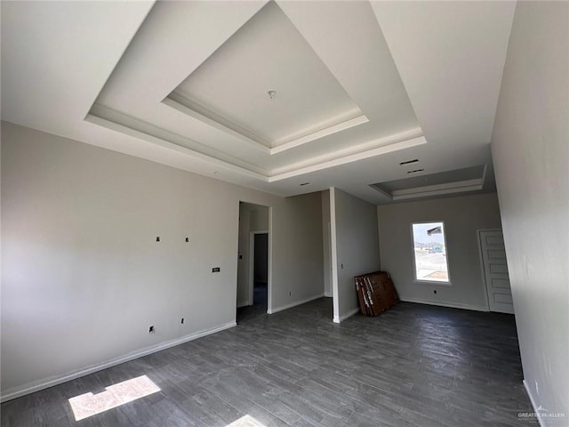 spare room with dark hardwood / wood-style flooring and a raised ceiling