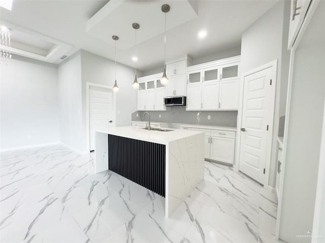 kitchen featuring white cabinetry, a center island with sink, pendant lighting, and sink