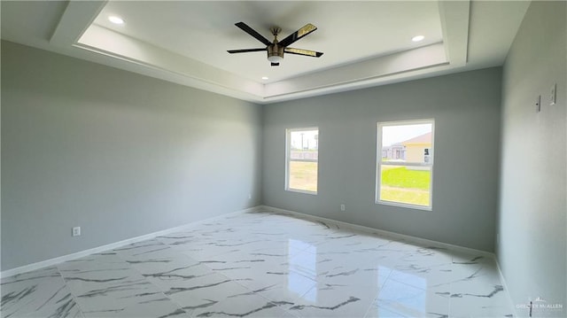 unfurnished room featuring ceiling fan and a tray ceiling