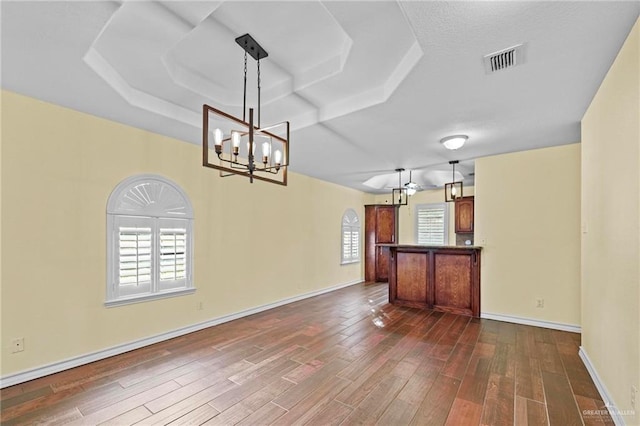 interior space featuring a notable chandelier, dark wood-type flooring, and a raised ceiling