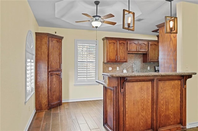 kitchen with tasteful backsplash, decorative light fixtures, kitchen peninsula, hardwood / wood-style flooring, and ceiling fan