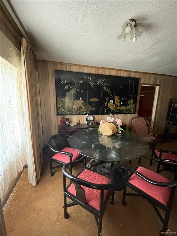 carpeted dining room featuring a textured ceiling and wooden walls