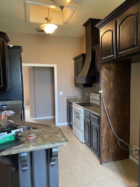 704 N Drennan St N, Edinburg, TX 78541 - kitchen featuring white electric range, light tile patterned floors, dark brown cabinets, and custom range hood