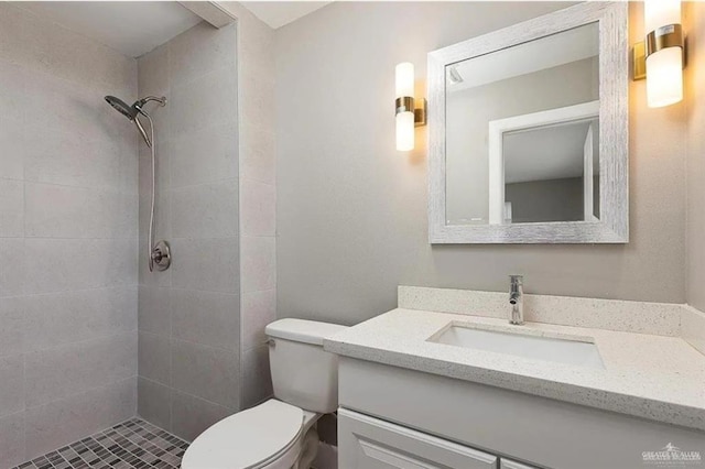 bathroom with vanity, toilet, and a tile shower