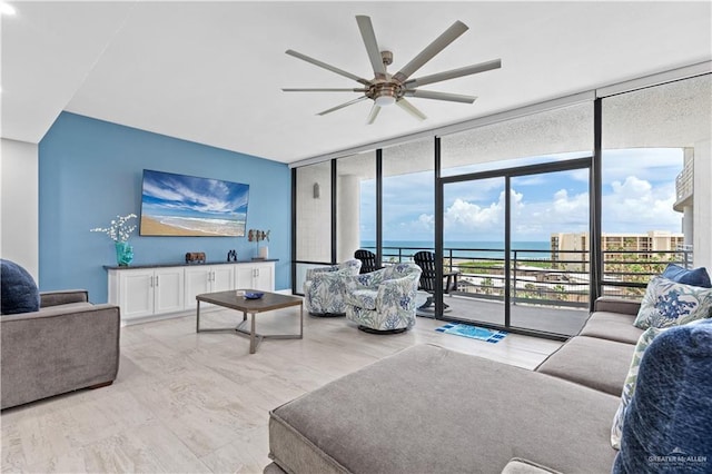 living room with a water view, a wall of windows, and ceiling fan