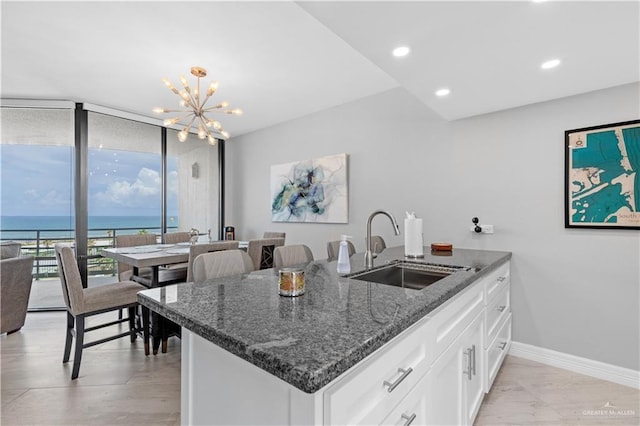1000 Padre Blvd, South Padre Island, TX 78597 - kitchen with a sink, dark stone counters, a chandelier, white cabinets, and baseboards